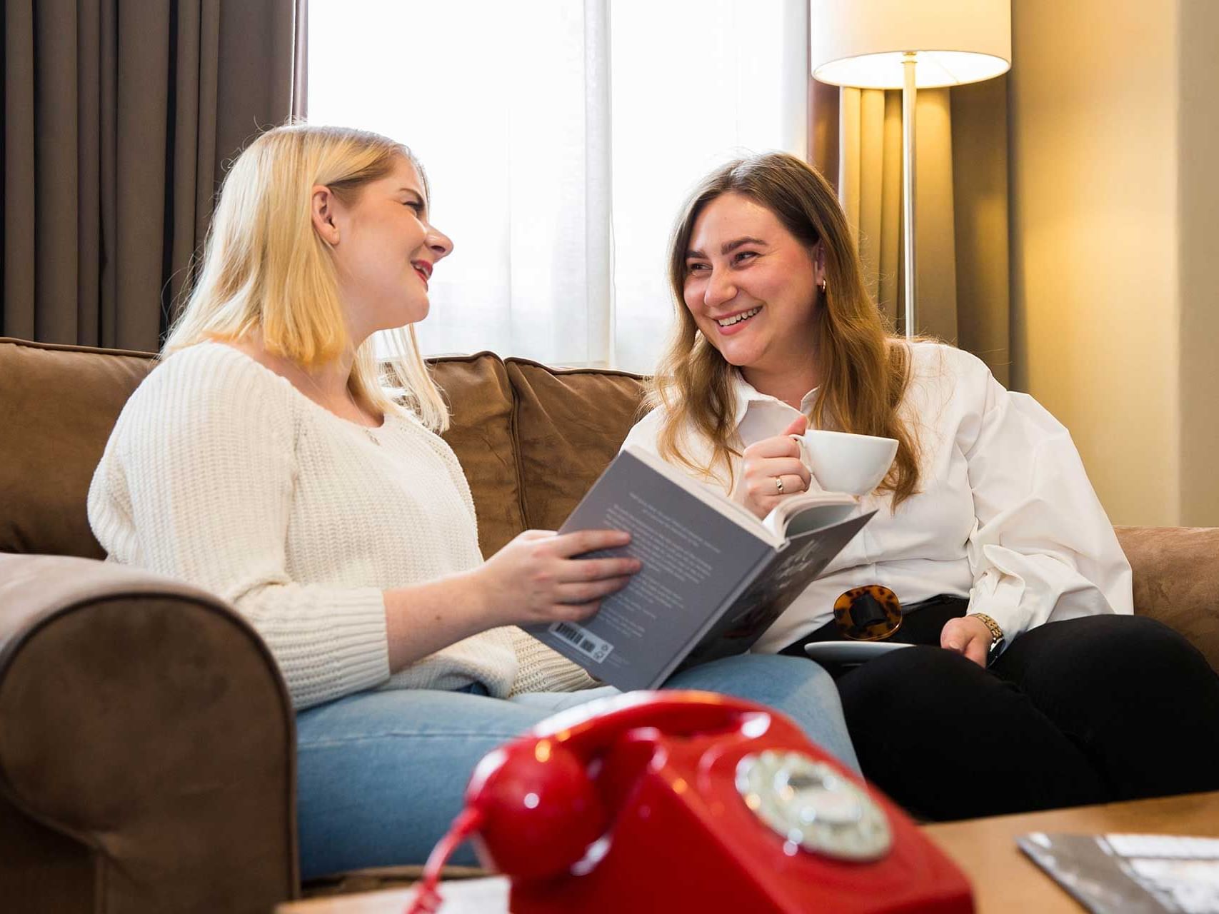 Two women sitting on a sofa while having coffee at The Met Hotel Leeds