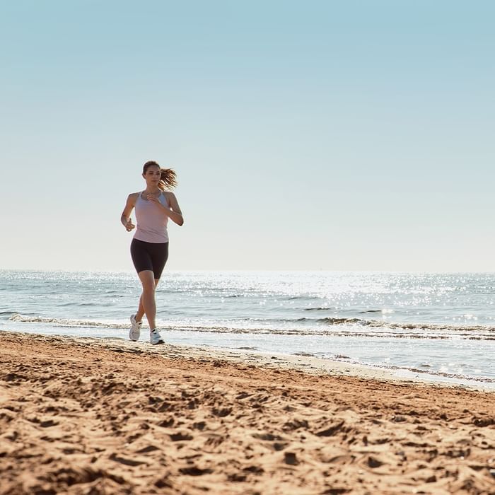 Frau joggt am Strand mit Meerblick bei Sonnenschein am Falkensteiner Hotel & Spa Jesolo