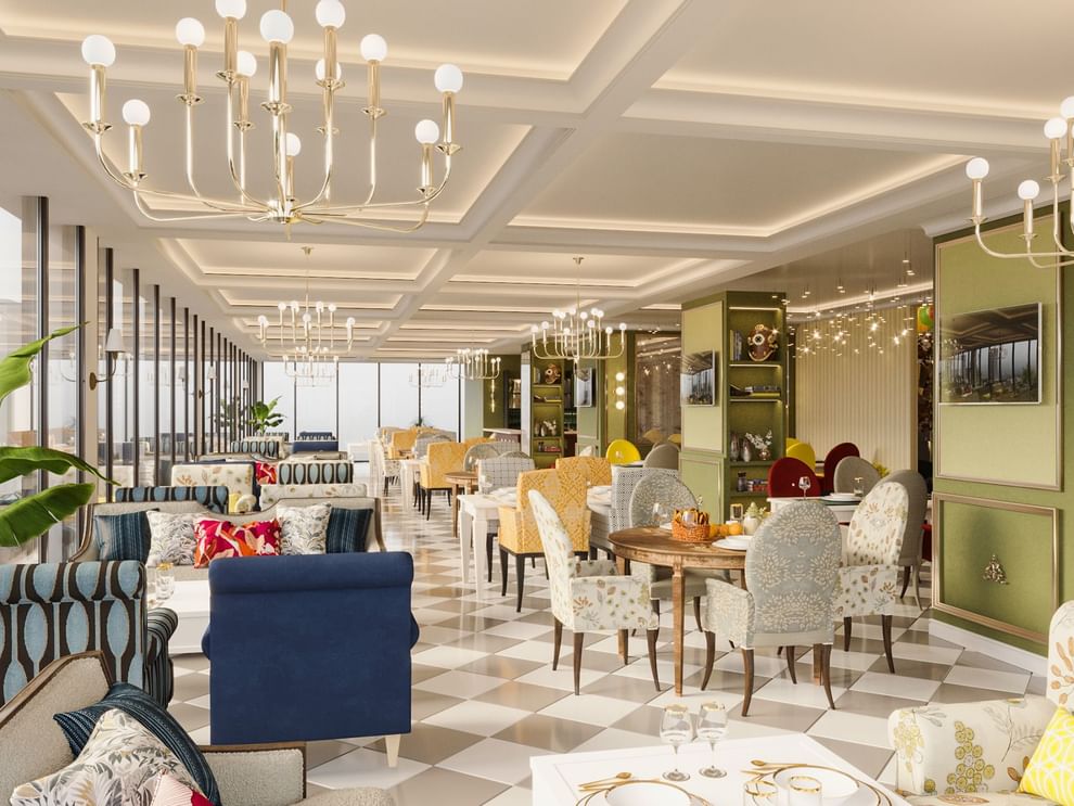 Patterned dining chairs by round wooden tables under gold chandeliers in The Tower View at Cantonal Hotel by Warwick Riyadh