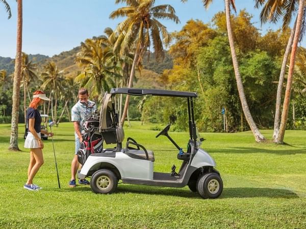 A Couple by a golf kart in a Golf Course at The Naviti Resort