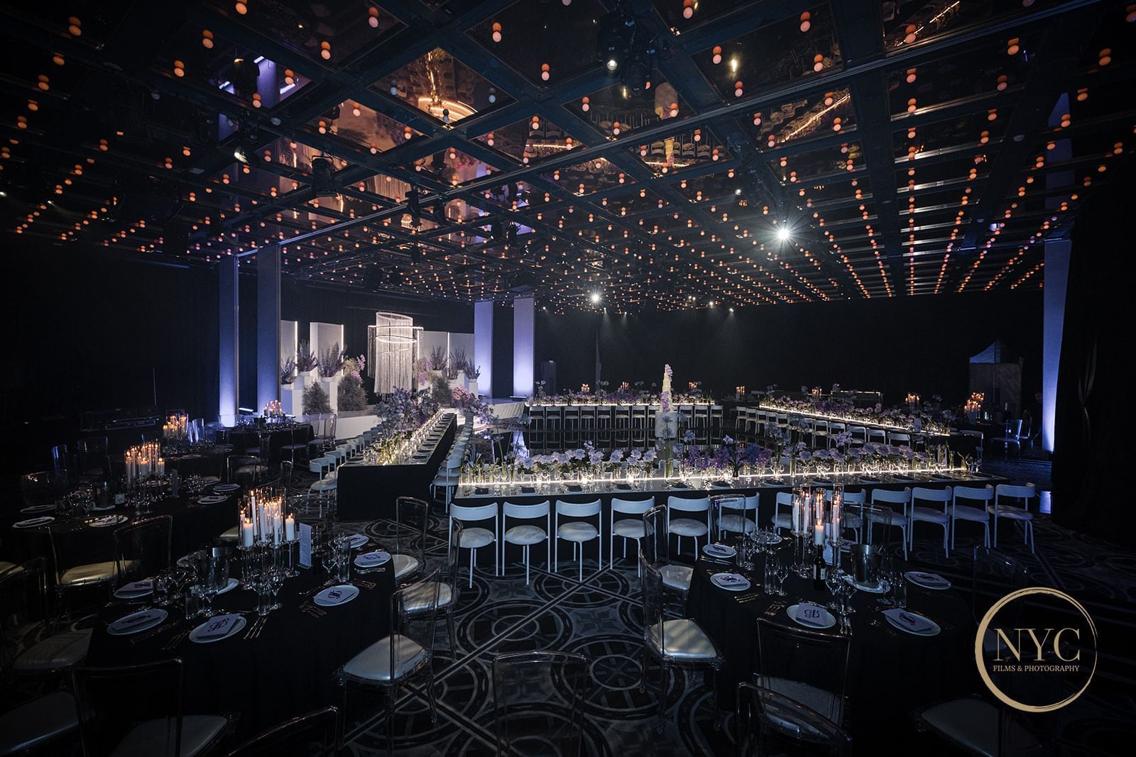 A large banquet hall with tables set for a formal dinner, dim lighting, and a decorative ceiling.