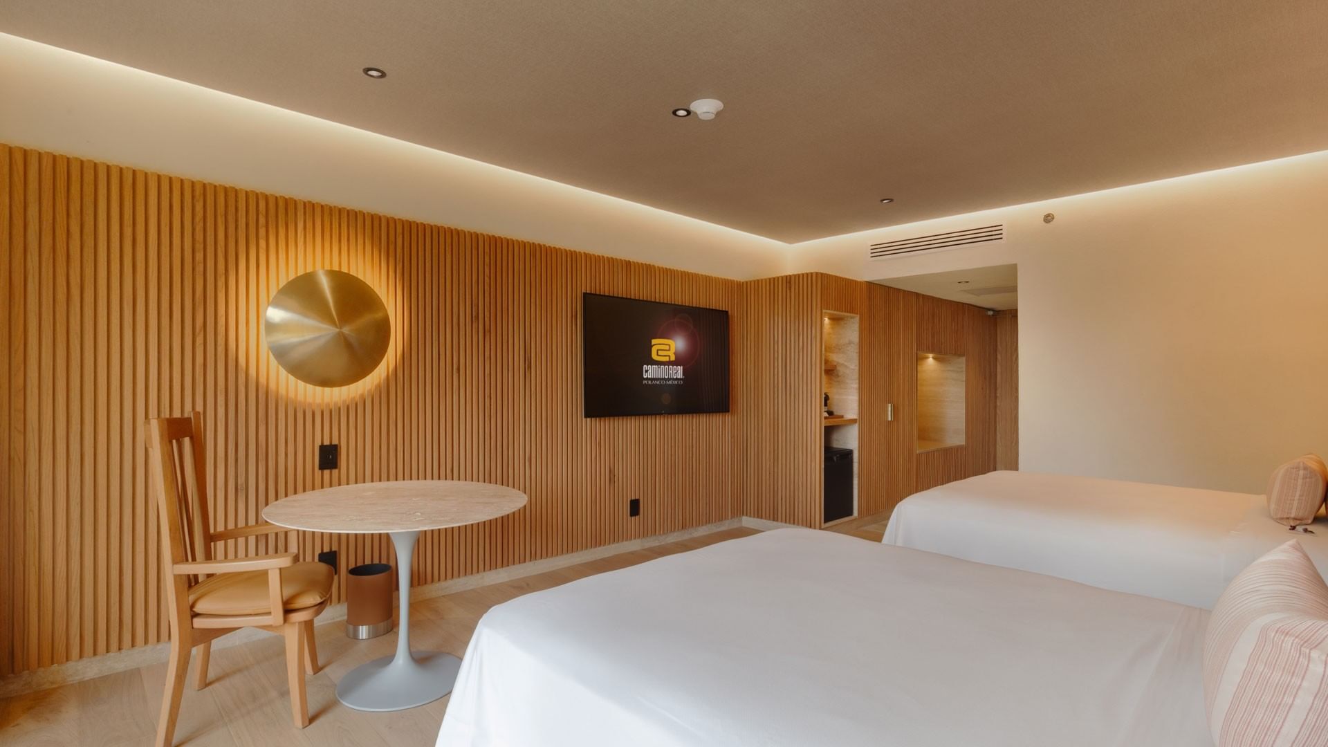 Habitación 2 Double Superior Camino Real Club con paredes de madera, mesa redonda y dos camas en Camino Real Polanco México