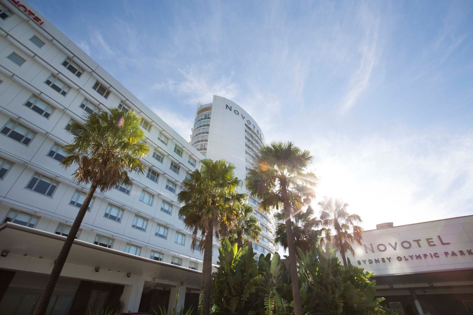 Exterior view of the Novotel Sydney Olympic Park surrounded by palm trees