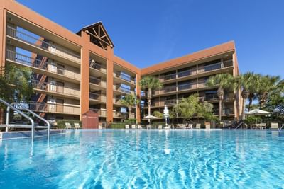 Low-angle exterior view of hotel building with pool at Rosen Inn Lake Buena Vista