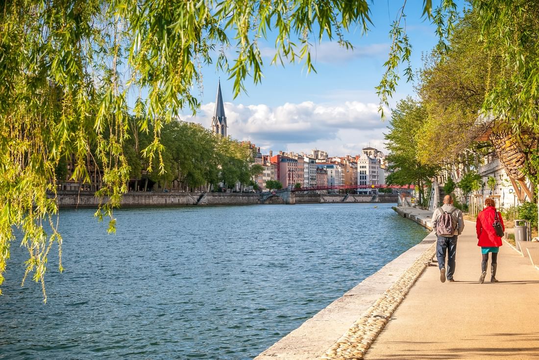 Couple walking along the Saône riverbank with a view of the city near Warwick Reine Astrid - Lyon