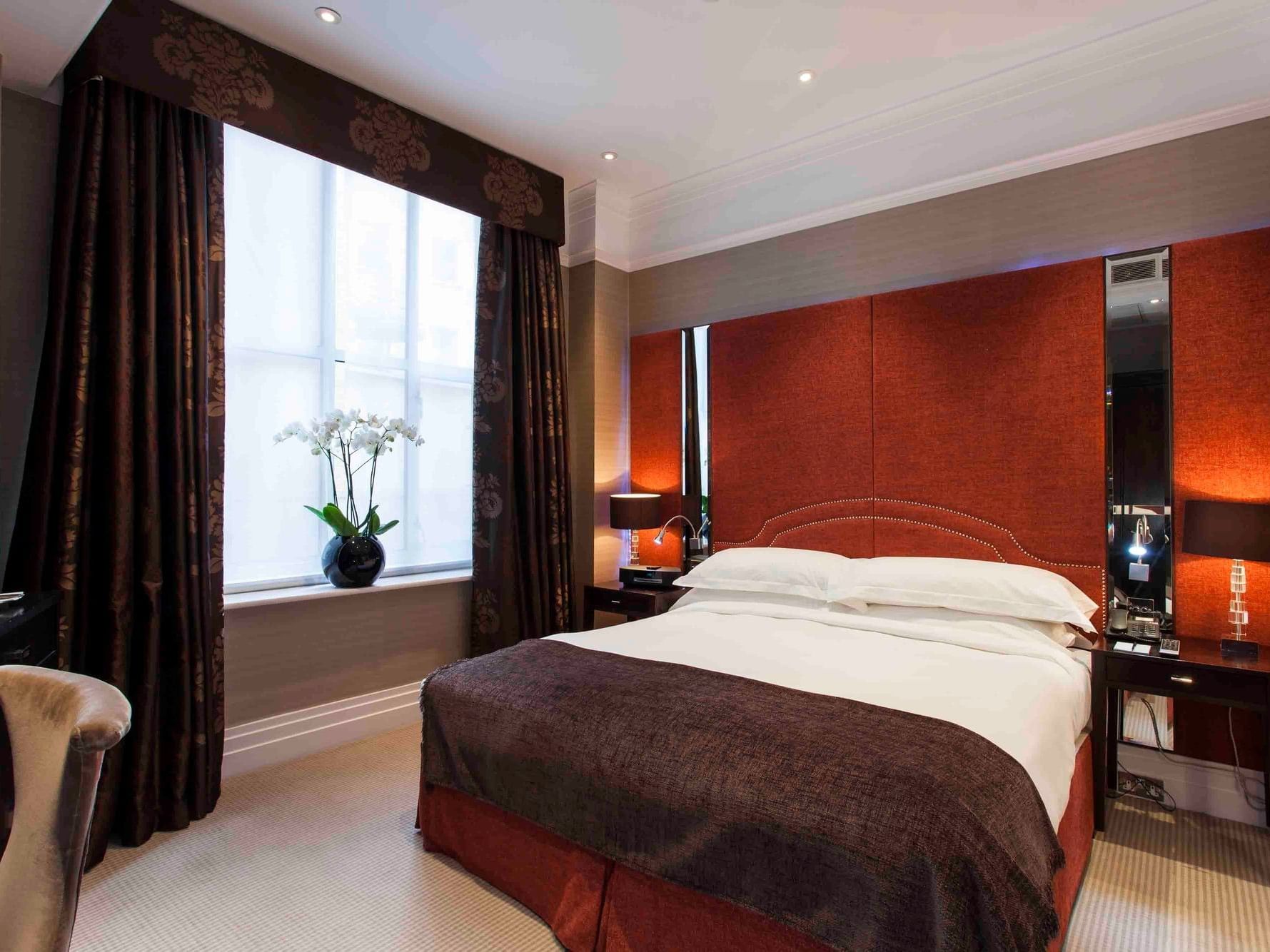 A bedroom with a large bed, window with curtains, and a chair beside a window at Warwick Hotels and Resorts