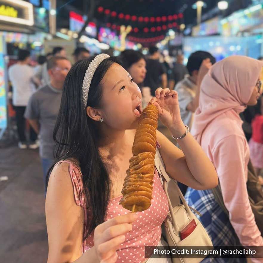 Lady diving into a potato skewer from Jalan Alor food stall near Imperial Lexis Kuala Lumpur, Places to eat in KL