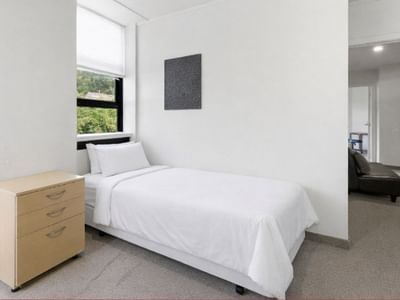 Clean room with white bed, dresser, and window at UniLodge Stafford House.