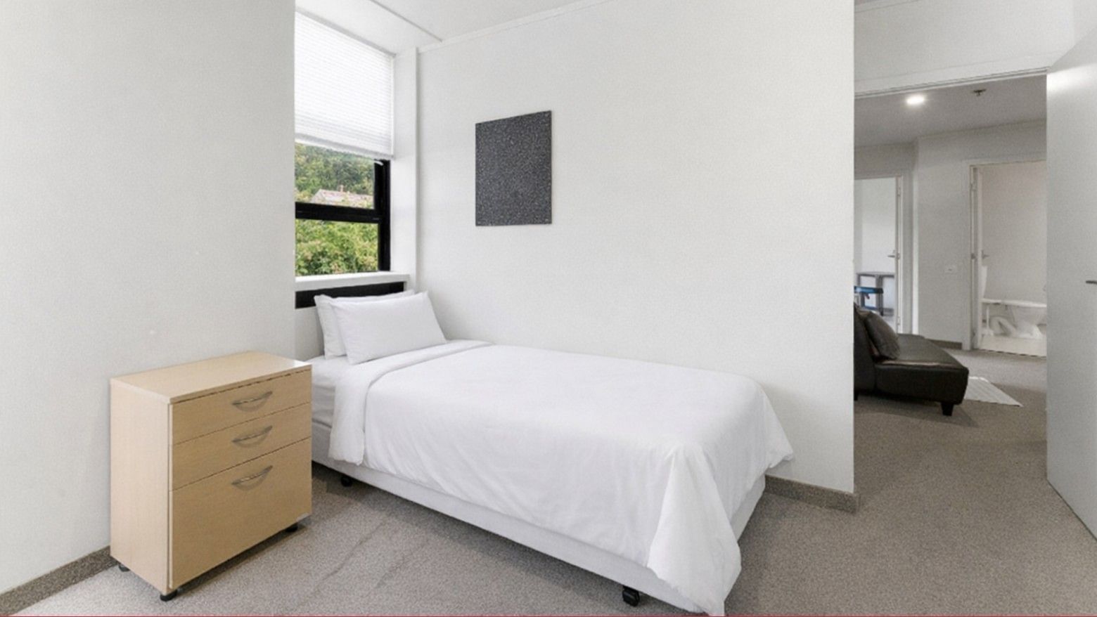 Single bed with white linens, a drawer, and a window in a tidy room at UniLodge Stafford House.