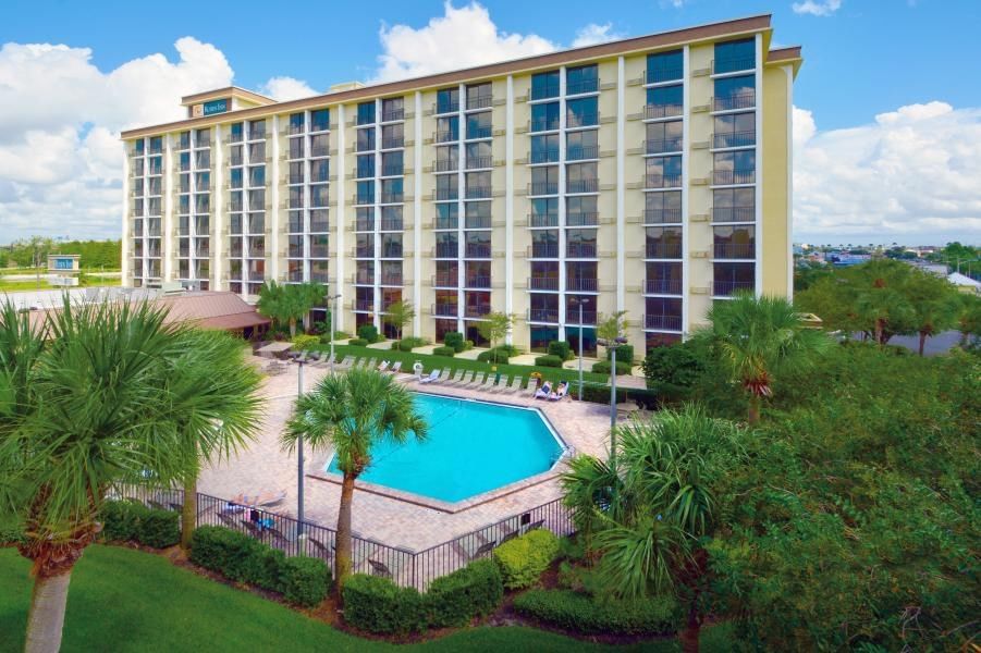 A tall Orlando hotel building stands behind a small pool surrounded by tropical foliage. 