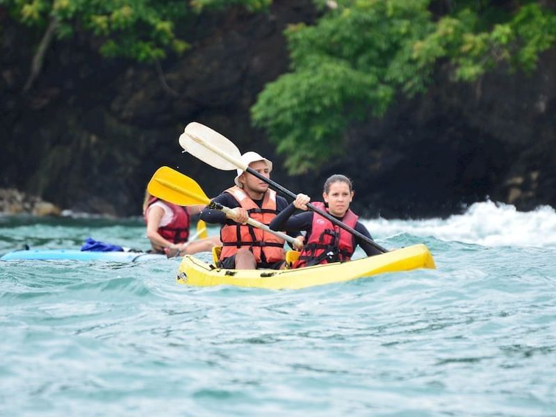 Couple kayaking in the sea surrounded by lush greenery near Los Altos Resort