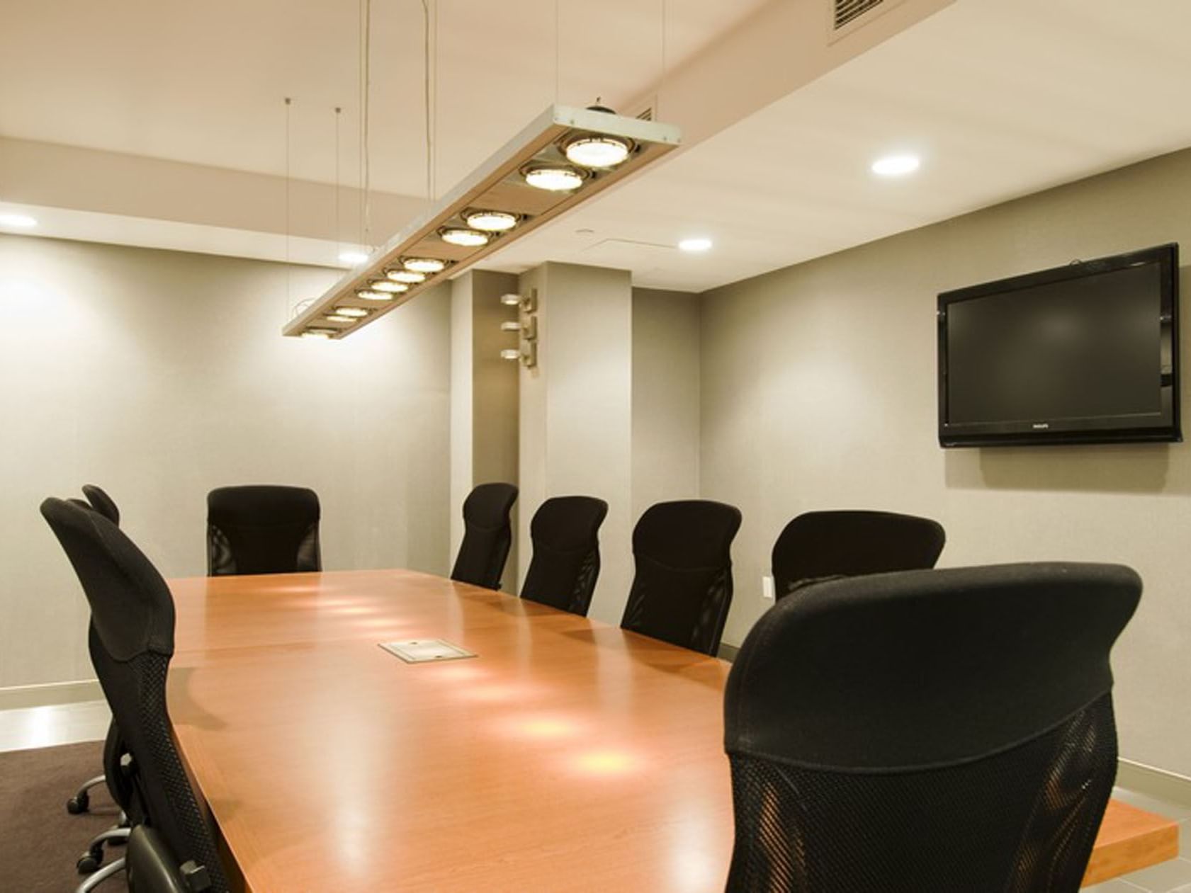Modern meeting room at Soho 54 Hotel in NYC, featuring a large table, ergonomic chairs, and TV