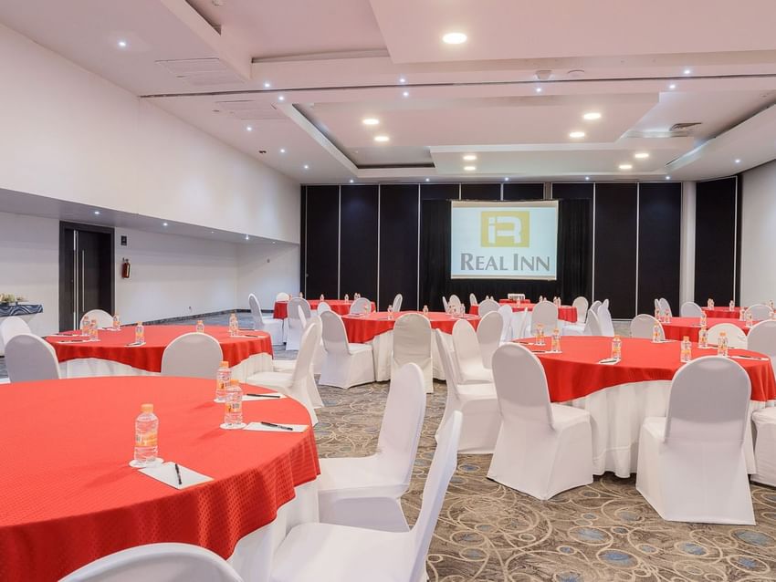 Florencia event space with banquet tables covered in vibrant red linens and white chair covers at Real Inn Tijuana