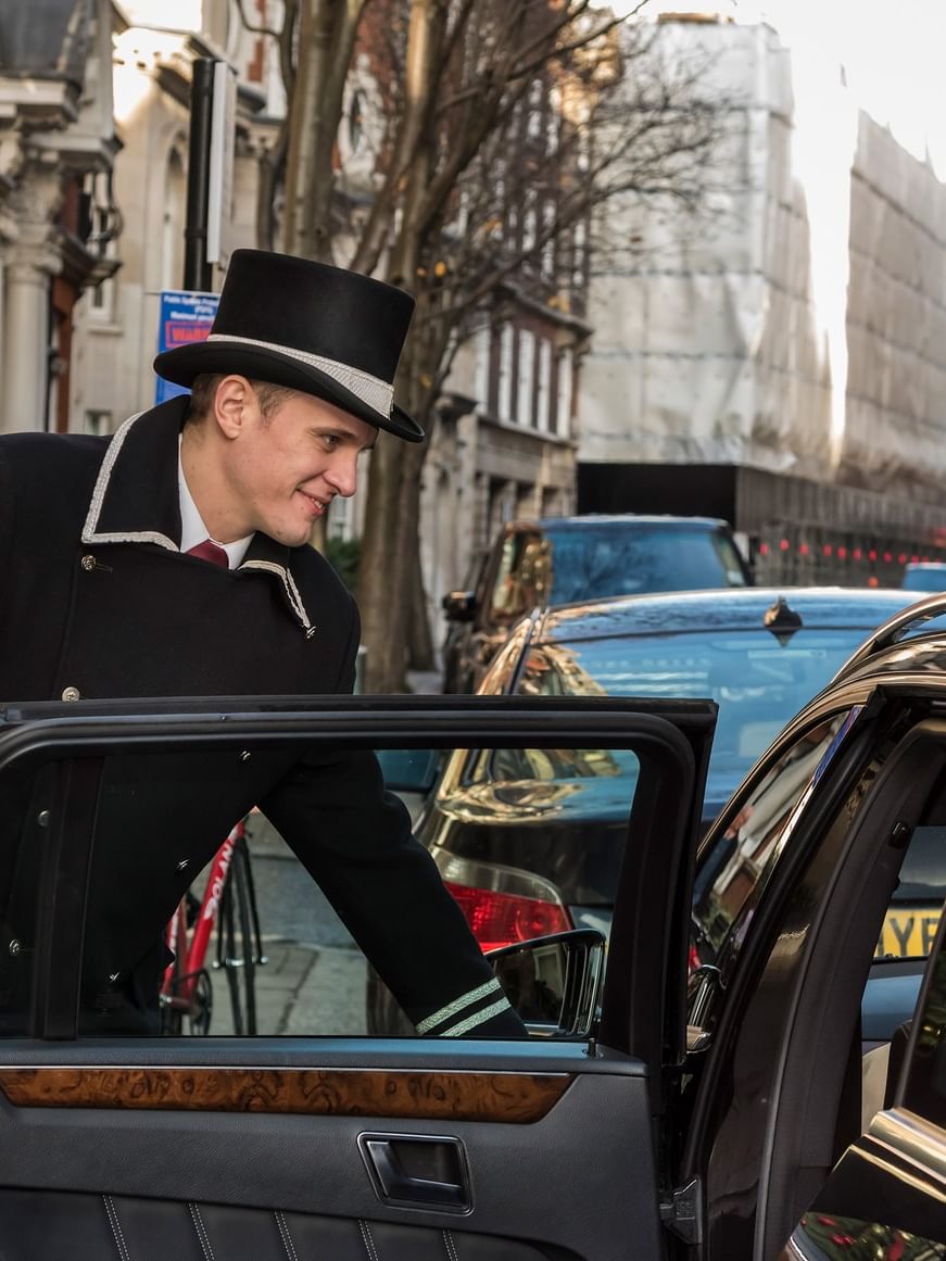 Man opening a car door on a busy London street near The Capital Hotel, Apartments & Townhouse