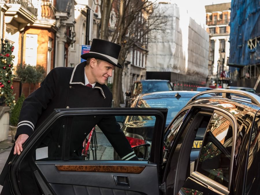 Man opening a car door on a busy London street near The Capital Hotel, Apartments & Townhouse