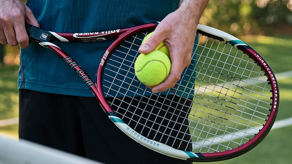 Close-up of a person holding a tennis racket and ball near Falkensteiner Hotel Antholz