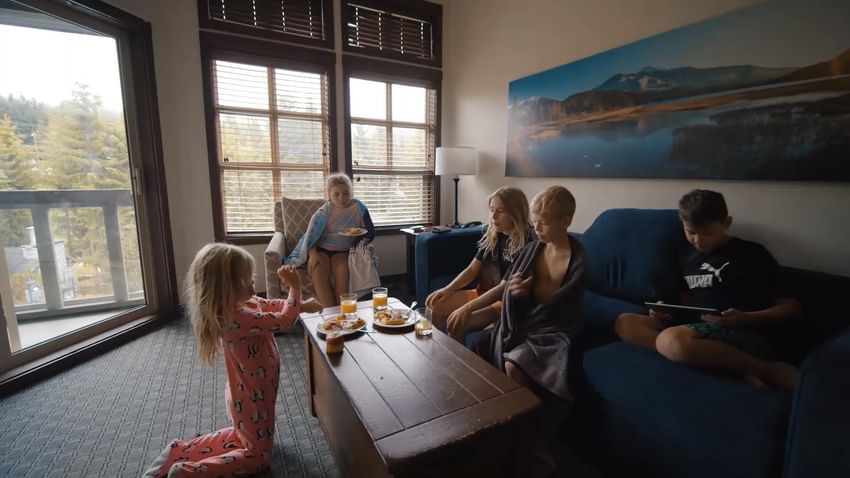 Family enjoying snacks in the living area in a suite at Blackcomb Springs Suites
