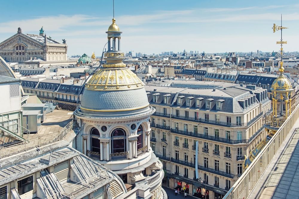 Scenic cityscape view with domes and rooftops under a bright blue sky, near Hotel Westminster Paris