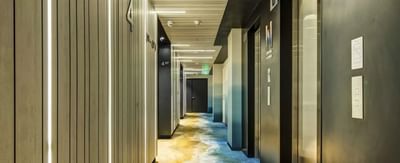 Hotel Nodo hallway with wood paneling and sleek overhead lighting, leading to the Standard King Room