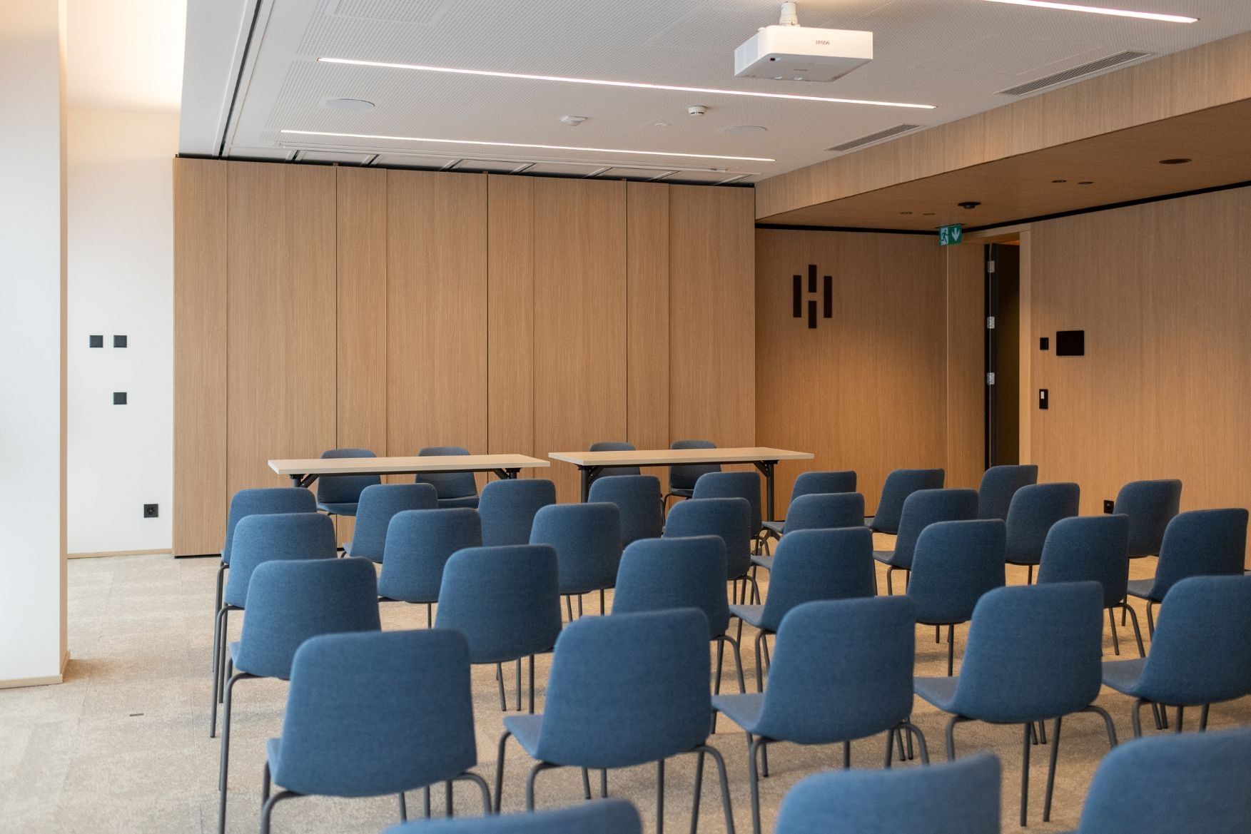 Theater-style conference space at Hotel des Innovations with wood paneling and rows of modern blue seating