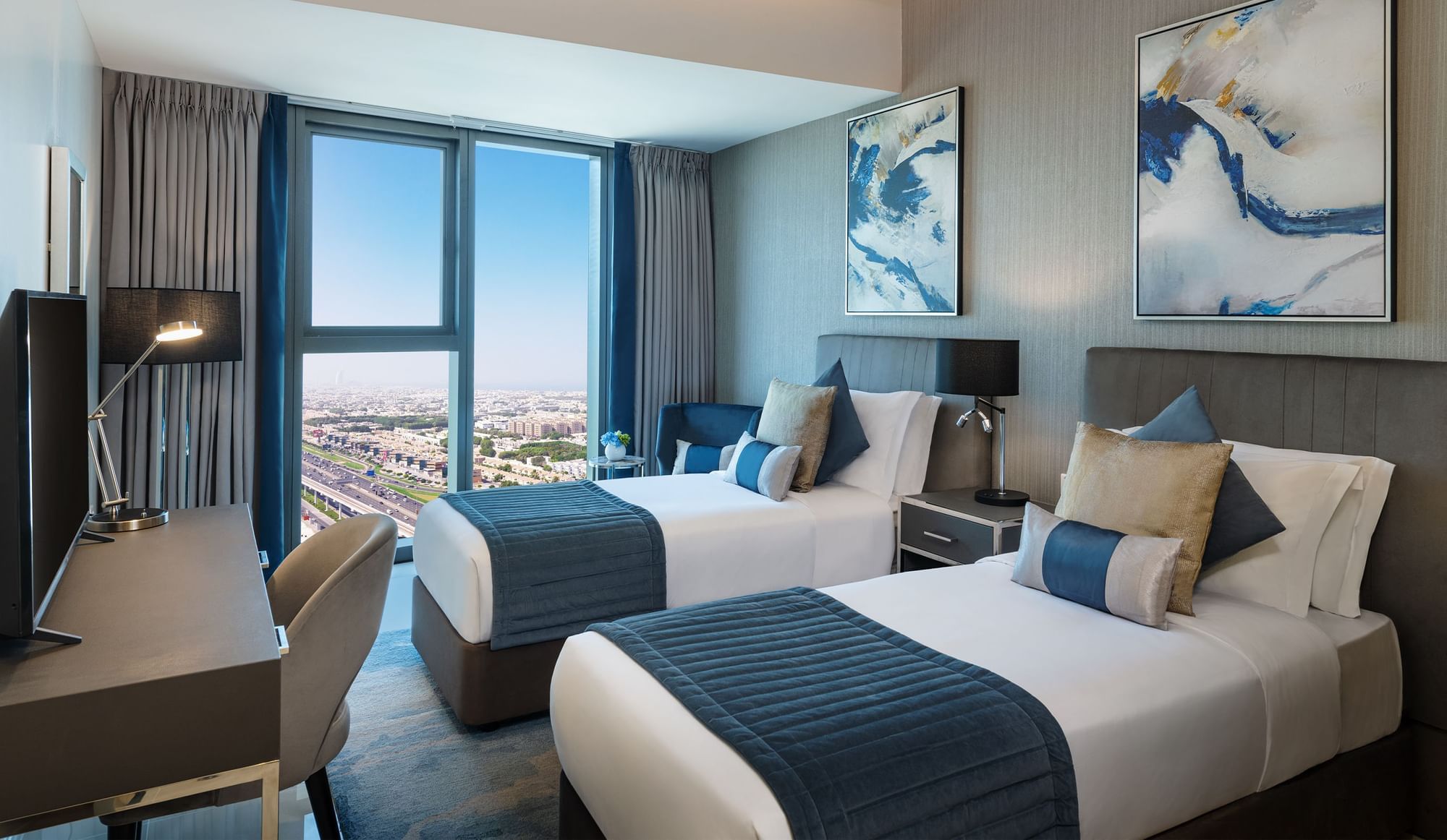 Work desk facing the cozy twin beds in a room with city view at DAMAC Maison Aykon City