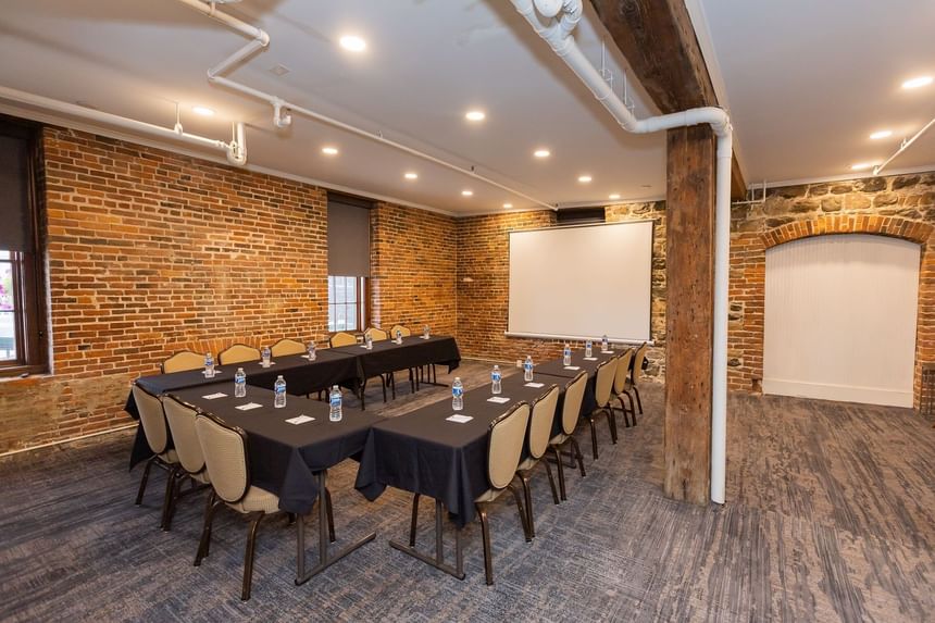 U-shaped table set-up with projector screen in Savannah Meeting Spaces at River Street Inn