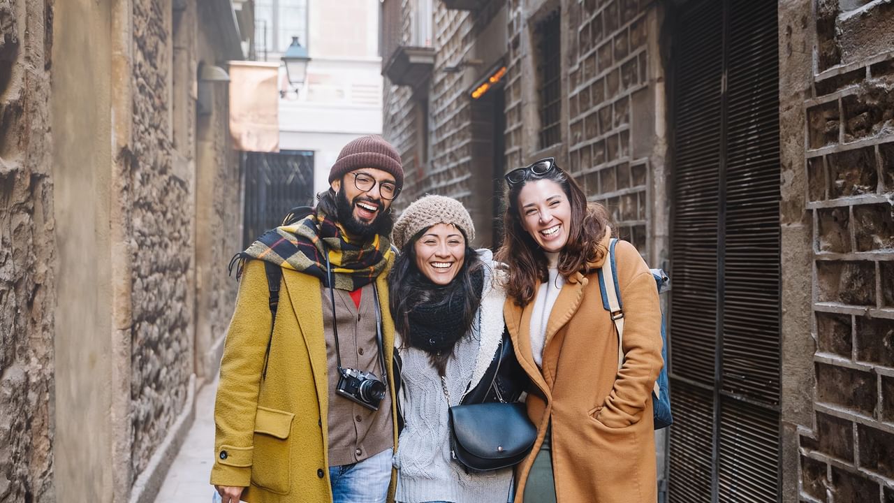 Three happy tourists pose together in a narrow street.