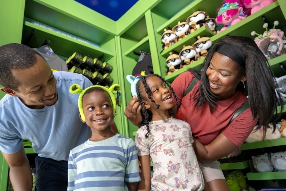 A man and a woman smile at kids wearing character headbands in a Universal souvenir shop. 