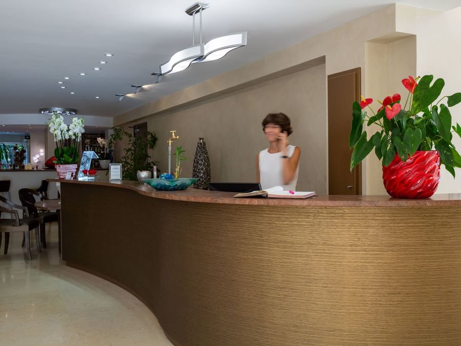 A receptionist at the reception desk in Hotel Les Trios Roses