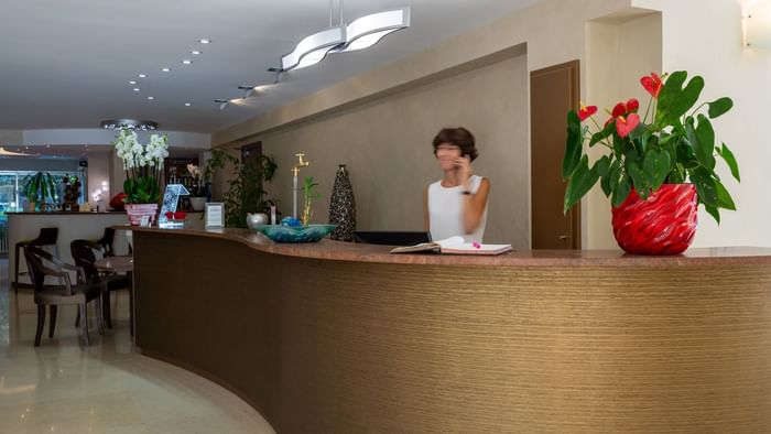 A receptionist at the reception desk in Hotel Les Trios Roses