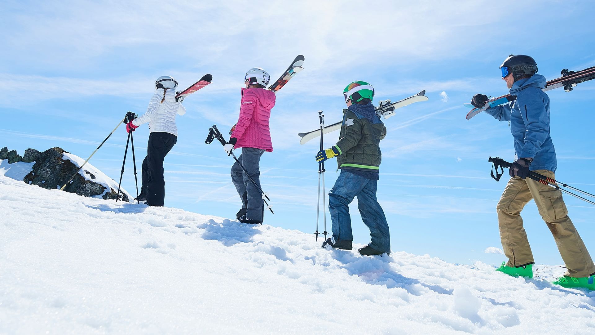 Skiers on snowy mountain raising their skis in triumph near Listel Whistler, a Coast Hotel