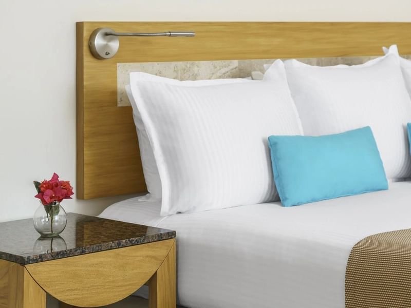 Cómoda cama con almohada blanca en habitación Premium en The Reef Playacar