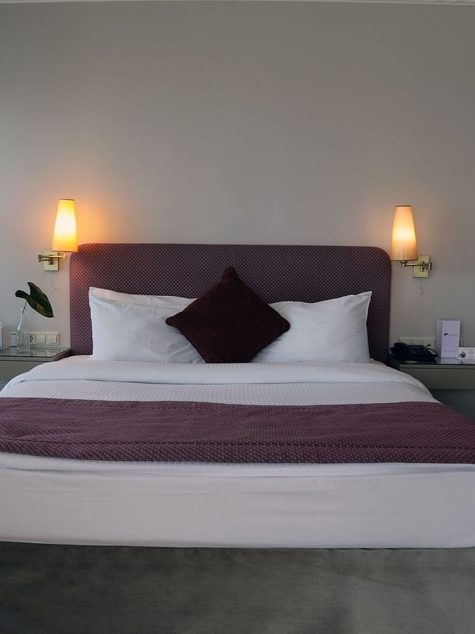 Bed with side tables under hanging wall lamps in the Senior Suite at Warwick Palm Beach Hotel