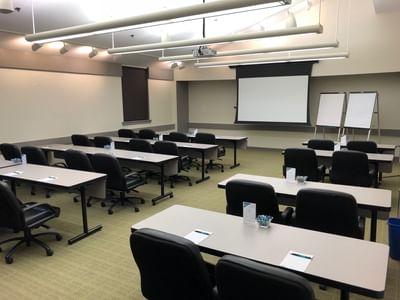 Modern conference room with rows of tables, chairs, projector screen, and whiteboards at Aramark Chauncey Conference Center