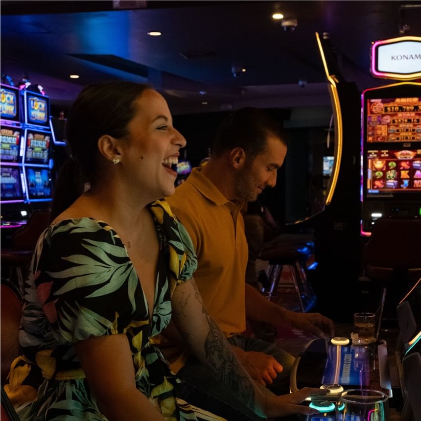 Pareja sonriente juega en máquinas tragamonedas con pantallas coloridas cerca de Megapolis Hotel Panama