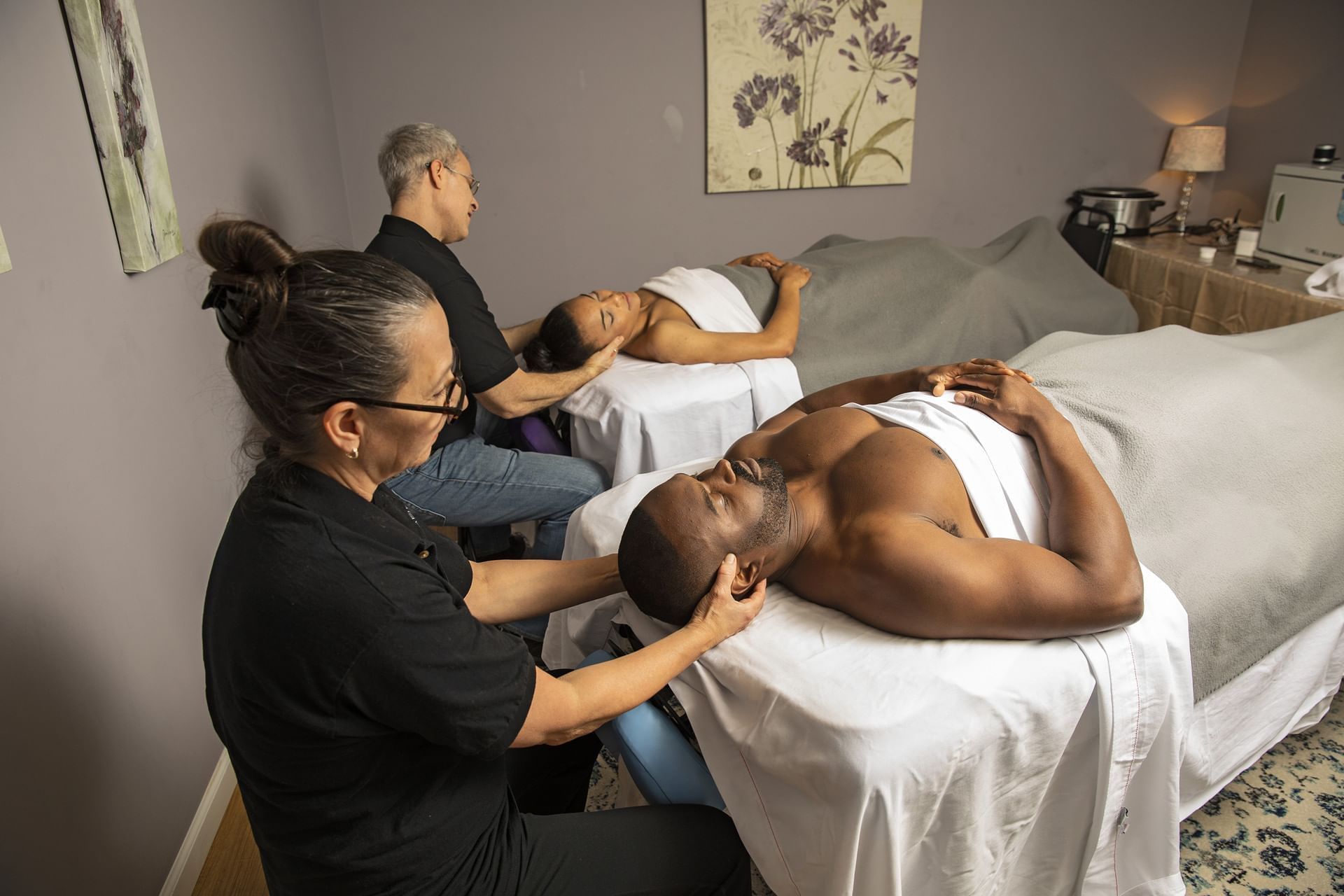 Two persons lie on massage beds and having an ayurvedic head massage at Cove Pocono Resorts