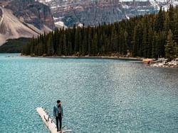 Man on a log in Banff & Lake Louise near Carriage House Hotel