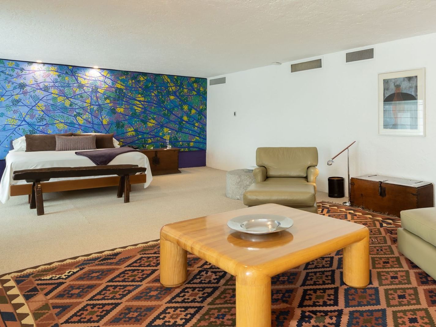 King Presidential Suite with a vibrant blue mural, a wooden table, and patterned rug at Camino Real Polanco Mexico