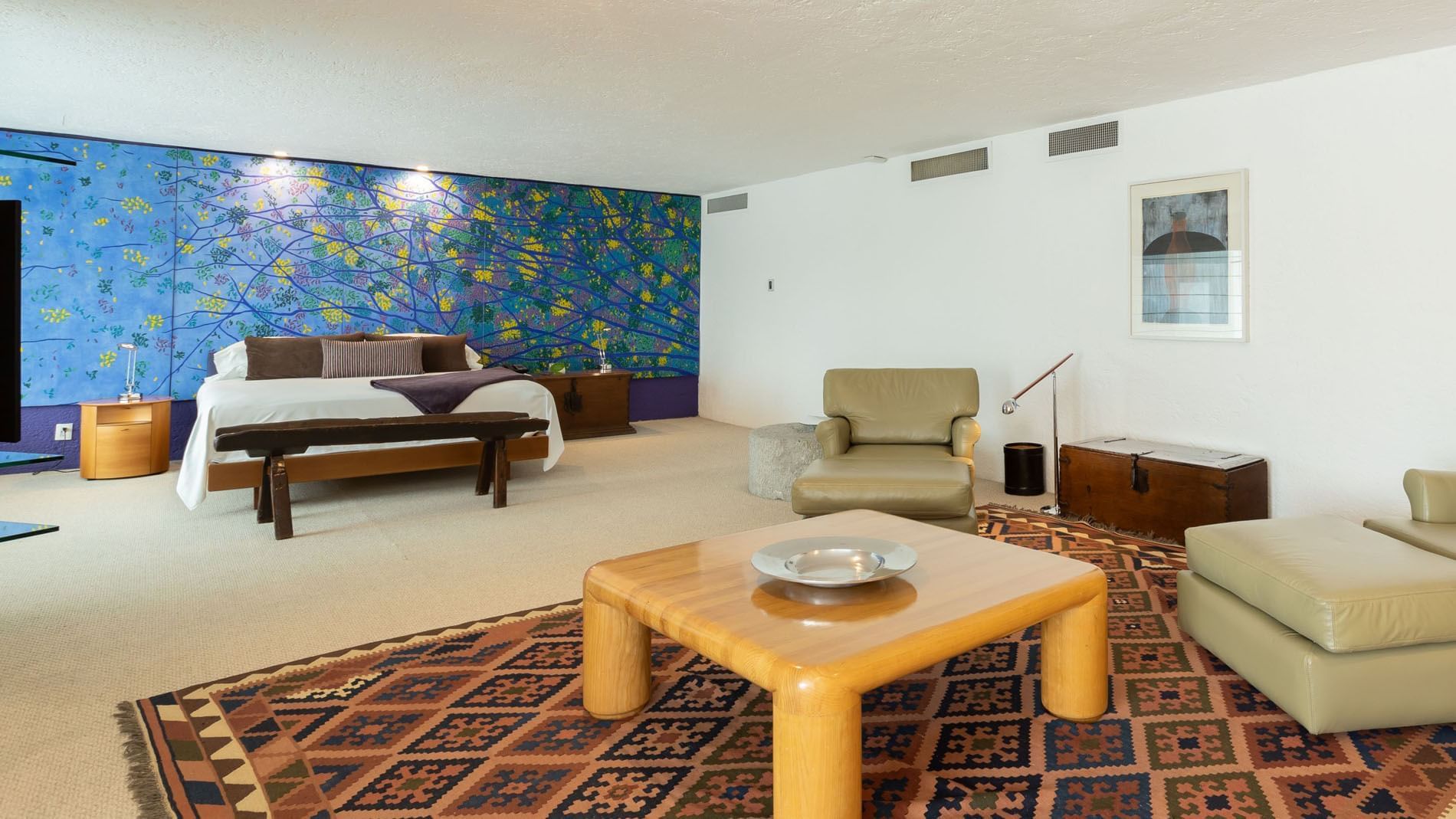 King Presidential Suite with a vibrant blue mural, a wooden table, and patterned rug at Camino Real Polanco Mexico