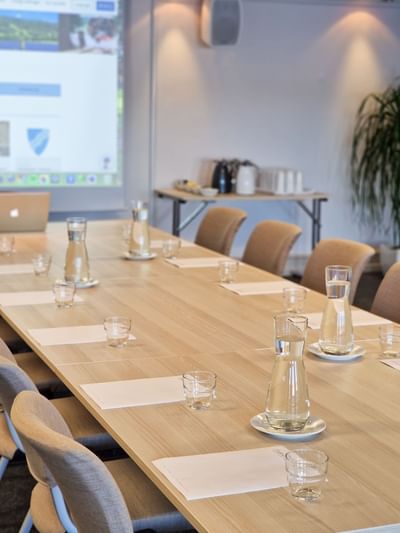 Modern conference room at Tyrifjord Hotel arranged with water pitchers, notepads, and a presentation screen in Norway