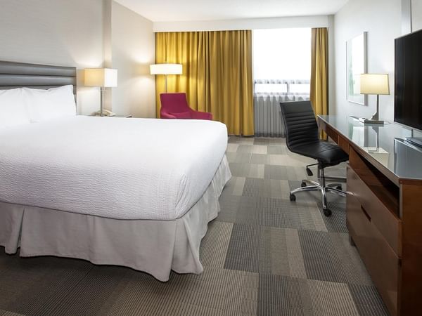 Coast Queen room with queen bed, work desk, flat-screen TV, and golden drapes at Coast Prince George Hotel