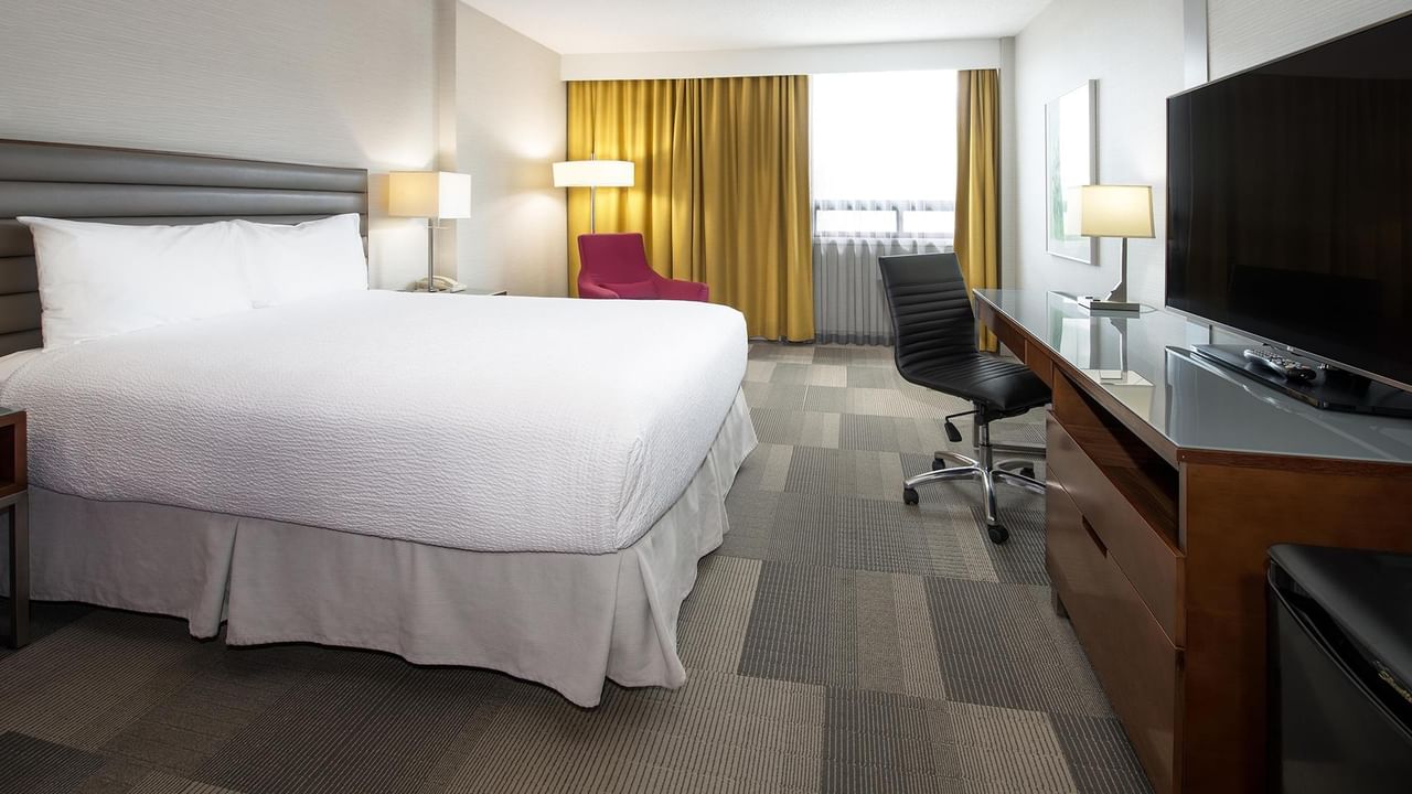 Coast Queen room with queen bed, work desk, flat-screen TV, and golden drapes at Coast Prince George Hotel