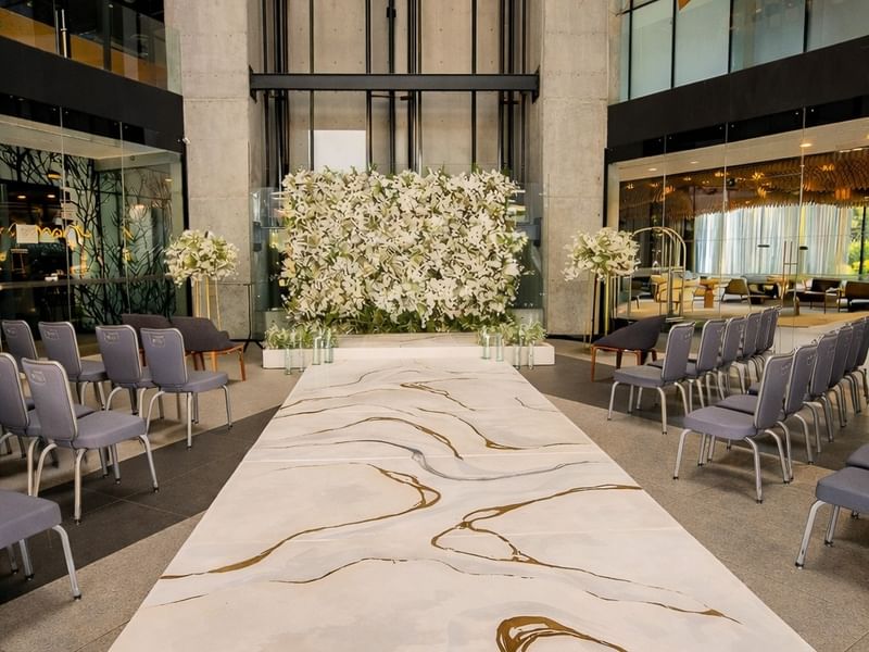 Elegant wedding ceremony setup with white floral backdrop and marble aisle at Live Aqua Monterrey.