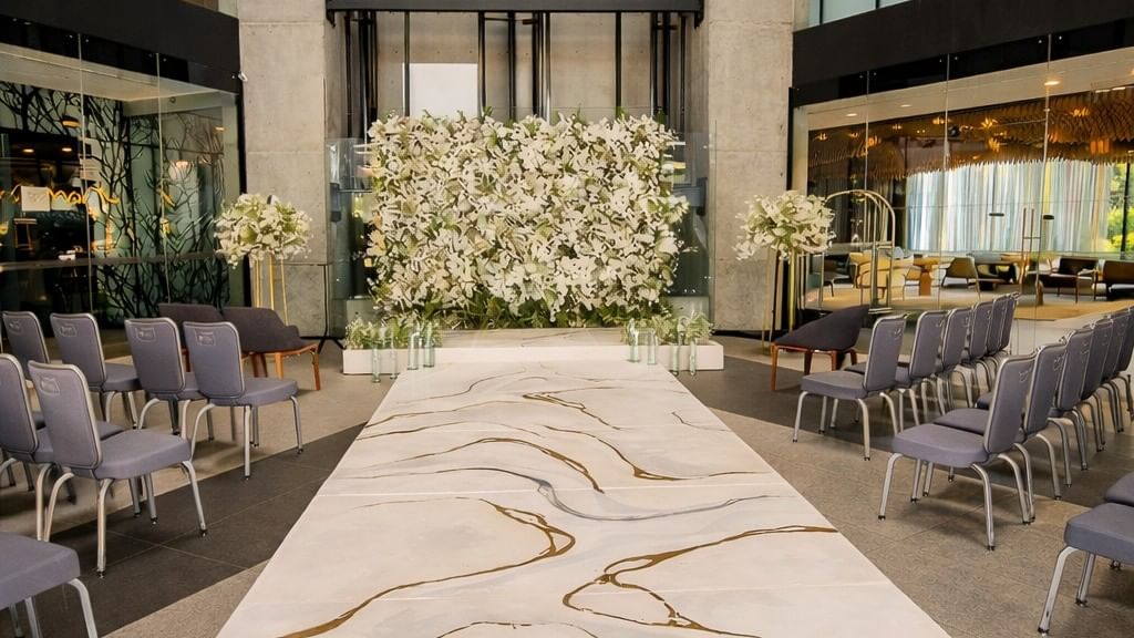 Elegant wedding ceremony setup with white floral backdrop and marble aisle at Live Aqua Monterrey.