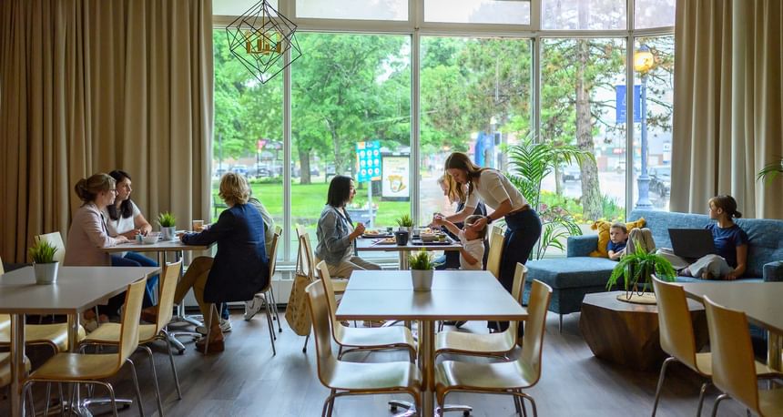 Group of families eating lunch together at the sunlit breakfast places in Moncton dining hall in the Rodd Moncton