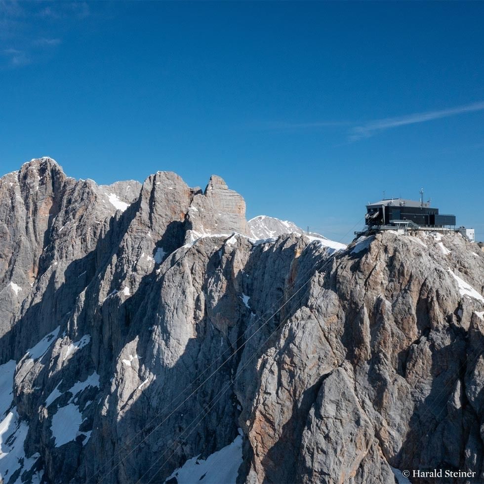 Panoramic view of the Dachstein Glacier with a building on top, suggesting a sunrise breakfast event.