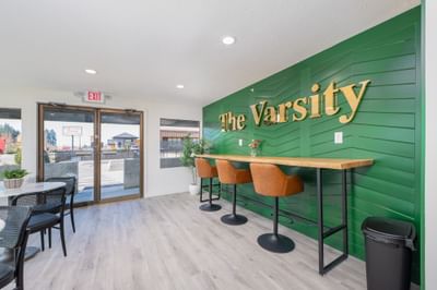 Leather barstools at a wooden counter against a green accent wall at The Varsity South