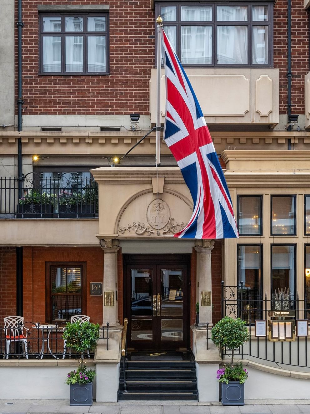 Front exterior of The Capital Hotel, Apartments and Townhouse with a British flag waving under a blue sky