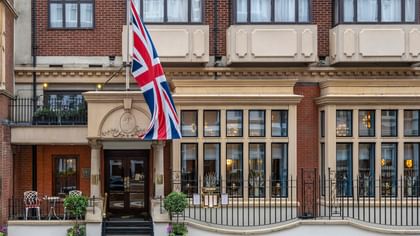 Front exterior of The Capital Hotel, Apartments and Townhouse with a British flag waving under a blue sky