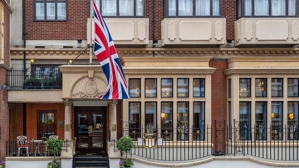 Front exterior of The Capital Hotel, Apartments and Townhouse with a British flag waving under a blue sky